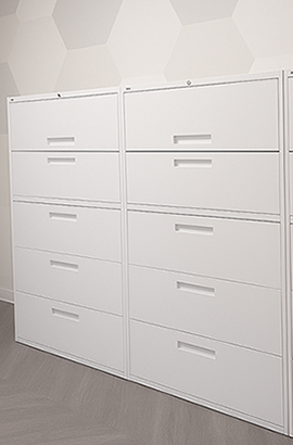 Modern office storage with two tall white metal lateral filing cabinets, each featuring four wide drawers with recessed handles and lockable top drawers.